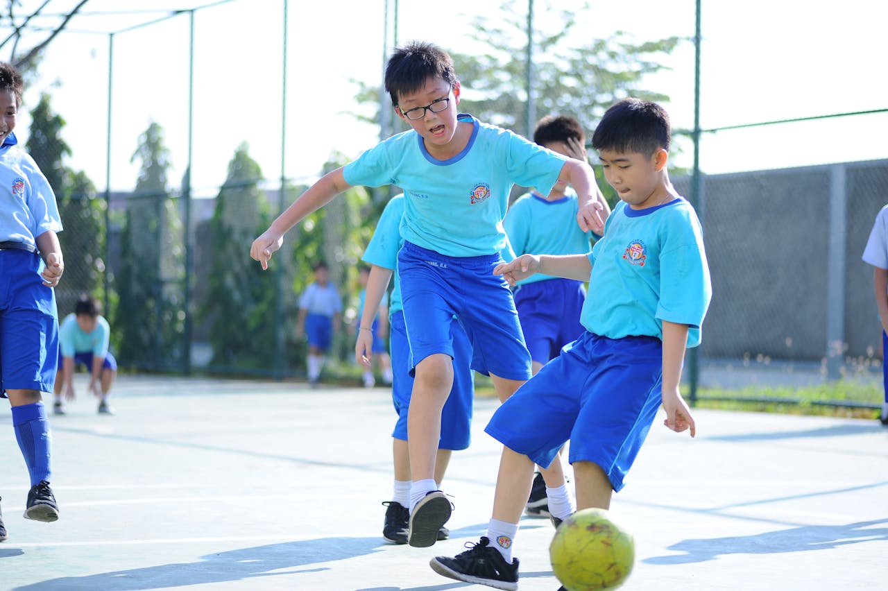 Young boys enthusiastically playing soccer on a sunny day at school.